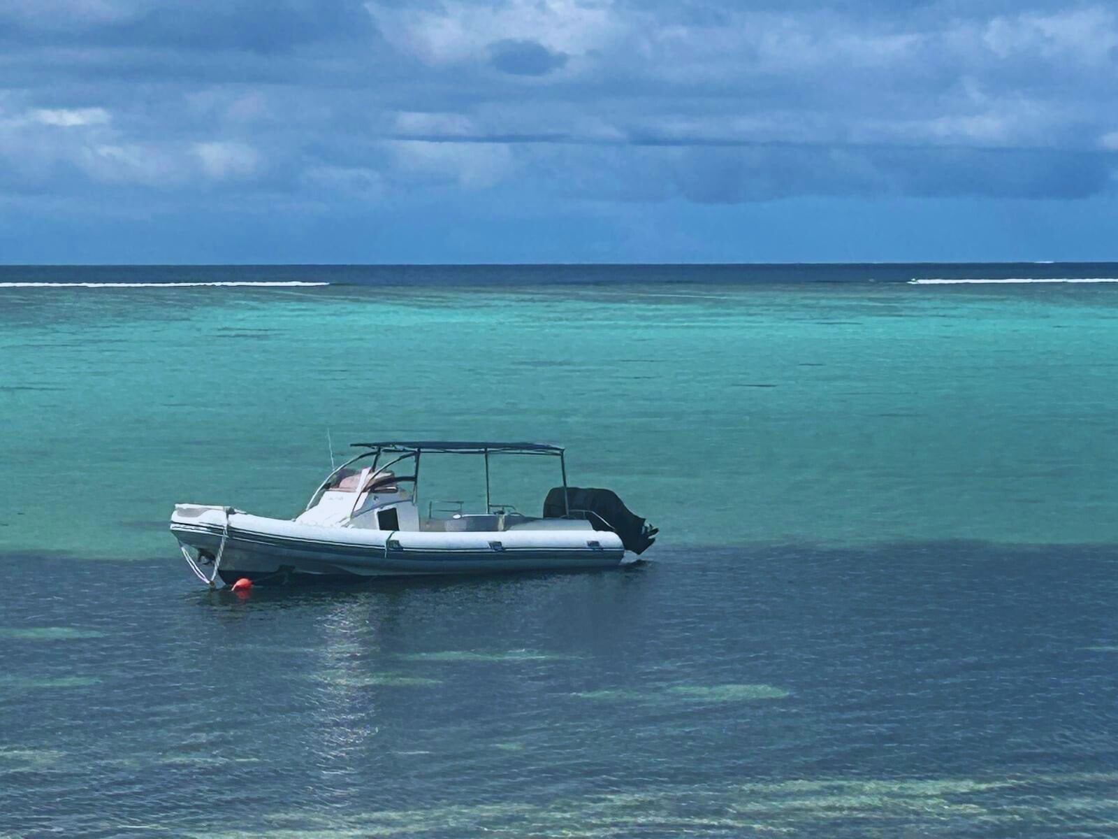Joy Bells boat with canopy, moored in turquoise water